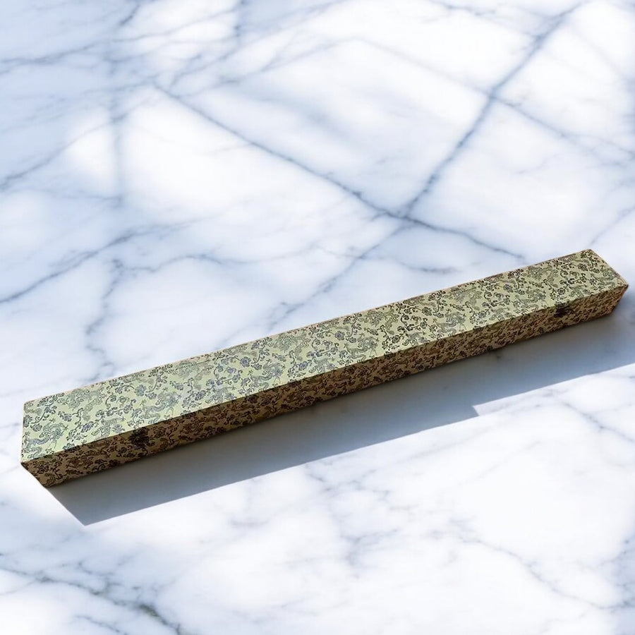 Closed gold-patterned Premium Katana Box on a pale marble background
