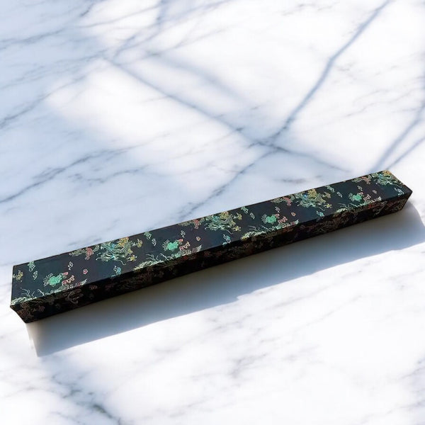 Premium Katana Box in dark green-black brocade with multicolor dragon-phoenix pattern and brass clasp on marble surface