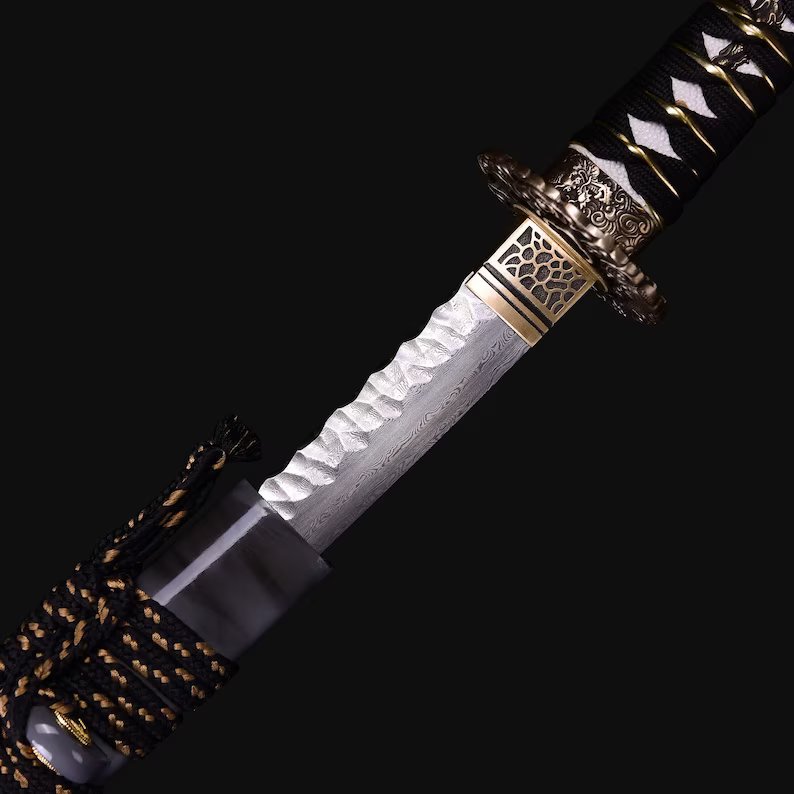 Shadow Moon Katana close-up showing white Damascus blade with hammered spine texture, copper openwork tsuba with floral-dragon relief, and black-white ito over genuine rayskin