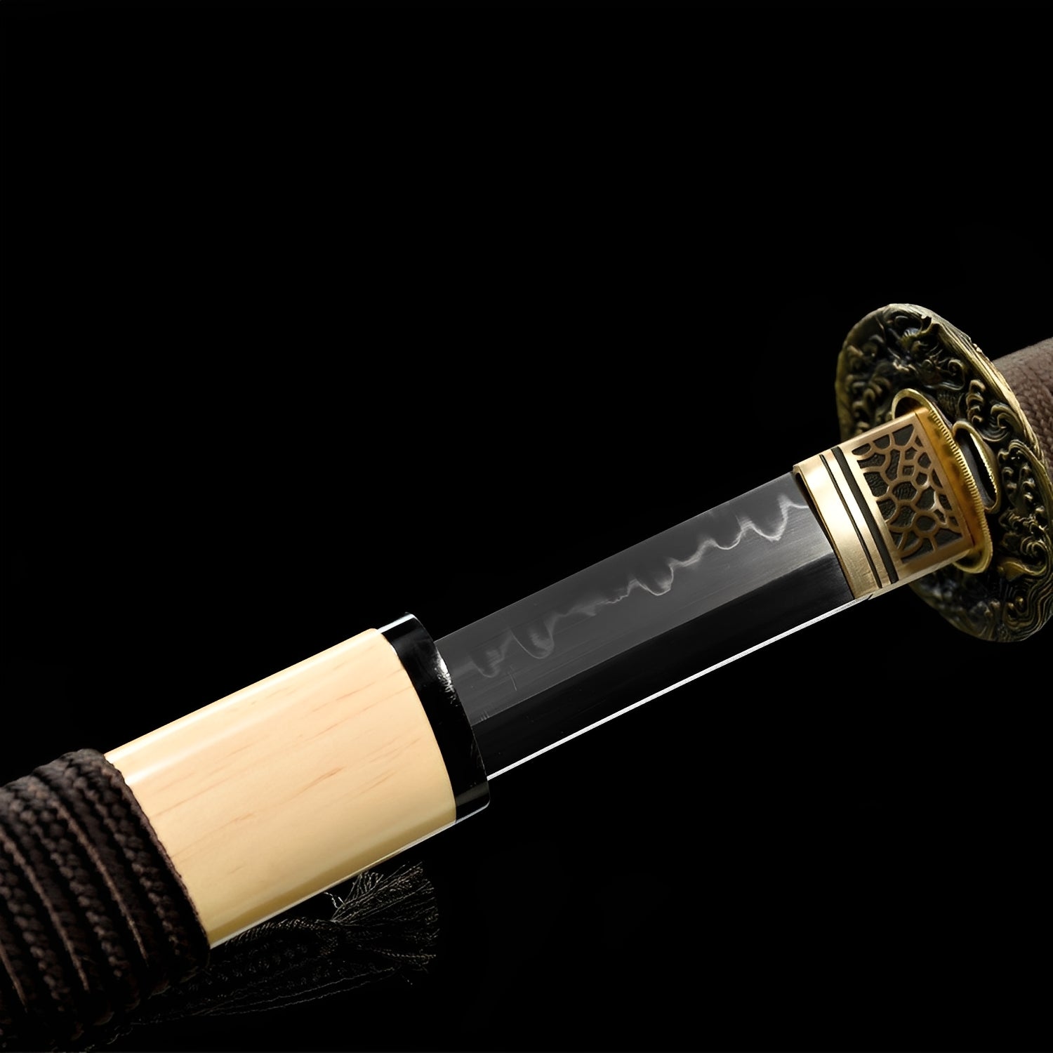 Shizukesa Katana close-up showing T10 blade with authentic clay-tempered hamon, antiqued brass dragon openwork tsuba with gold rim, honeycomb habaki, and dark brown cotton ito with blue menuki over genuine rayskin