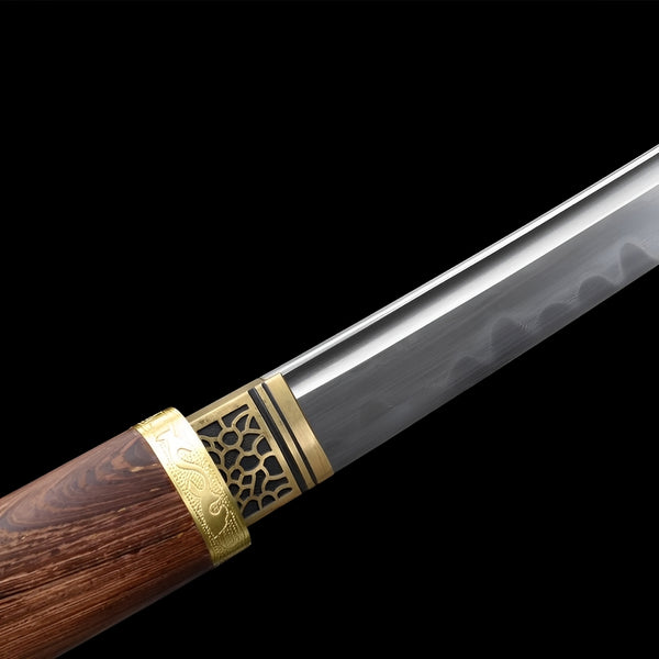 Wooden katana sword close-up showing polished 1060 blade with visible hamon, brass openwork tsuba with crackle pattern, and natural wood handle with brass bands