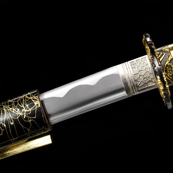 Kinkuro Katana close-up showing polished 1060 blade with hamon, chrome-gold dragon openwork tsuba, silver engraved habaki, and gold PU leather ito with chrysanthemum menuki over synthetic rayskin