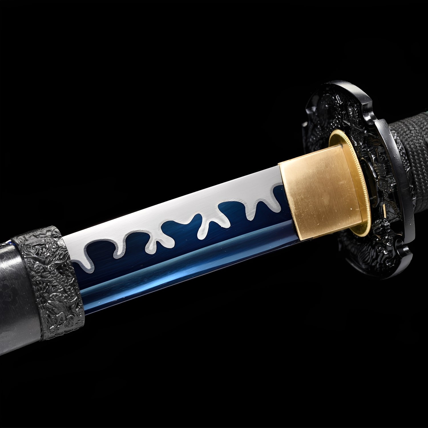 Shirakawa Katana close-up showing blue 1060 blade with white flame-drip overlay and hamon, black iron-alloy dragon tsuba, brass habaki, and green-red-black Tachi-style cotton ito over synthetic rayskin