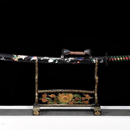 Shirakawa katana saya detail showing pink-white cherry blossom flowers and green leaves painted across glossy black lacquer surface