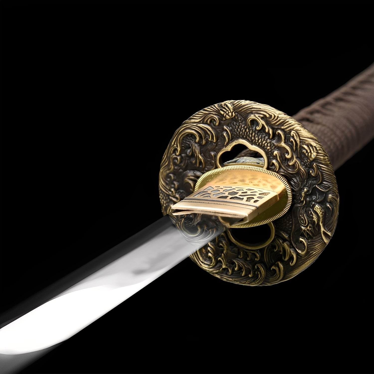 Shizukesa katana tsuba detail showing antiqued bronze dragon relief with gold outer rim and brass honeycomb habaki beneath