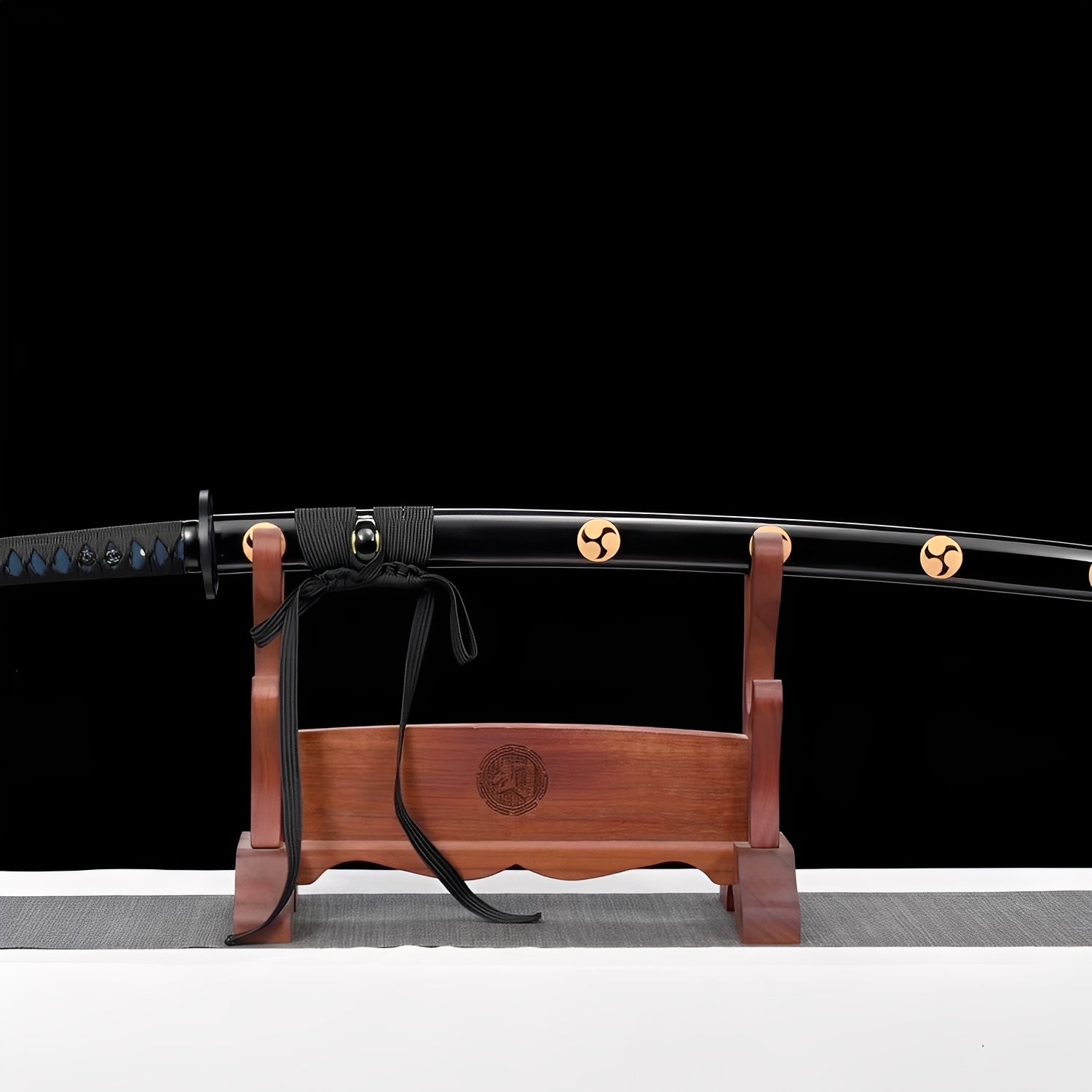 Triple tomoe katana complete set with black lacquer saya, gold crest emblems, wooden kojiri with carved mitsudomoe, and natural wood display stand