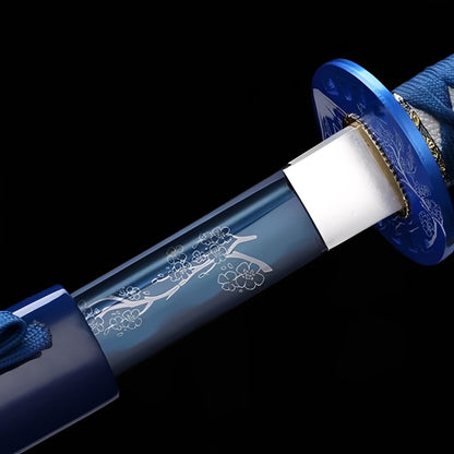 Blue Sakura Katana close-up showing translucent blue acrylic tsuba with white cherry blossom engravings, brass habaki, and blue cotton ito over white synthetic rayskin