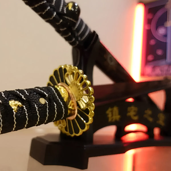 Yoru no Kage ninjato tsuba detail showing elaborate brass mandala with radiating geometric cutouts in gold and silver